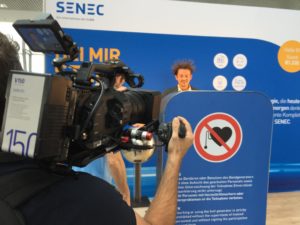 Kameramann bei Messe TV Dreh filmt Mann mit elektrisiertem Haar